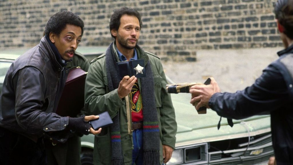 Danny Costanzo e Ray Hughes mostrano i distintivi in una scena di Una perfetta coppia di svitati (1986).